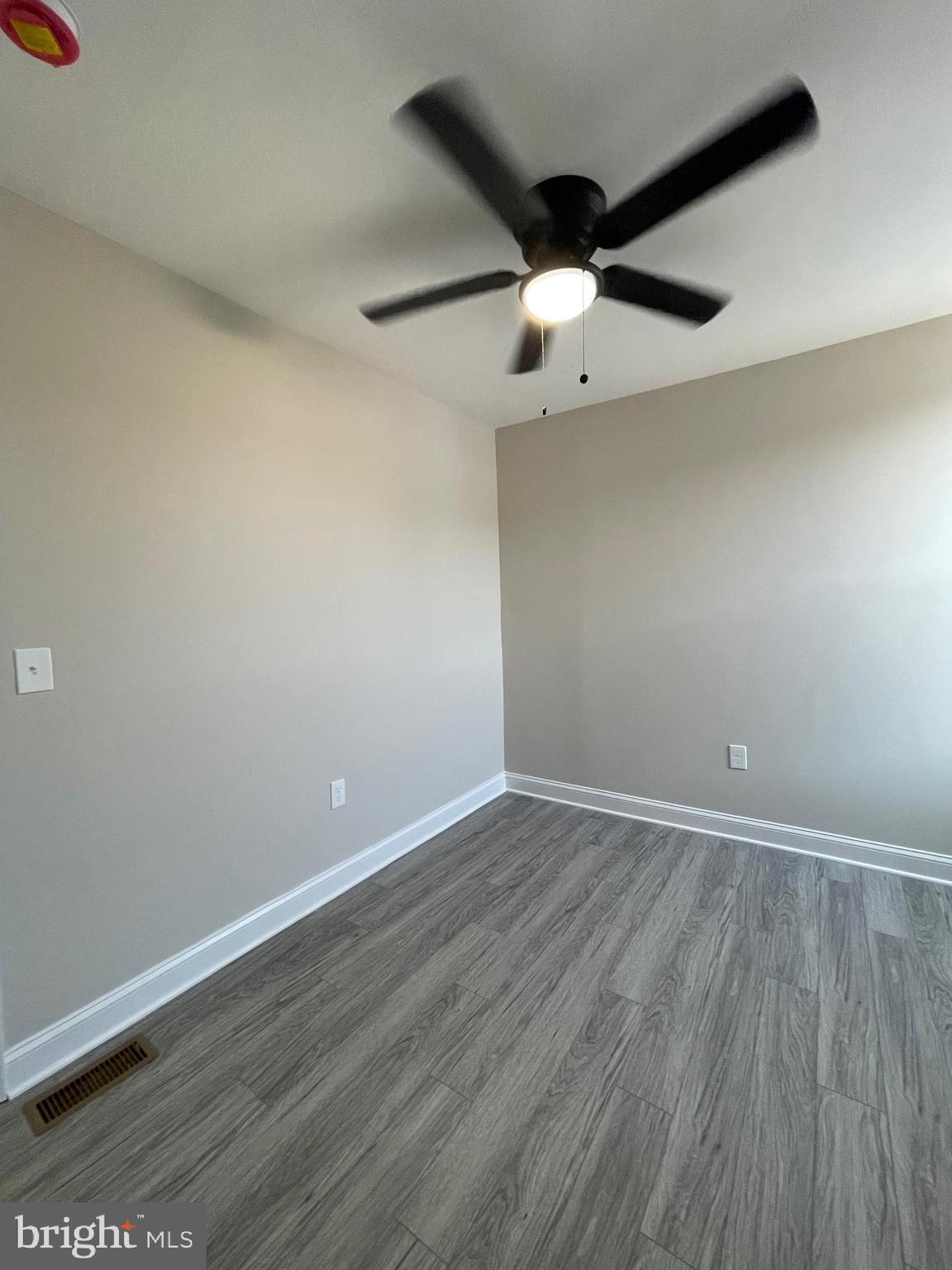 1806 East Lanvale Street Baltimore, MD 21213 - Photo 16 of 23 an empty room with wooden floor ceiling fan and window