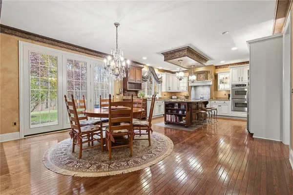 a view of a dining room and livingroom with furniture wooden floor a chandelier