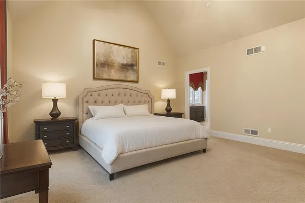 a bedroom with a bed and a lamp on dresser