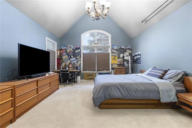a bedroom with bed tv and chandelier