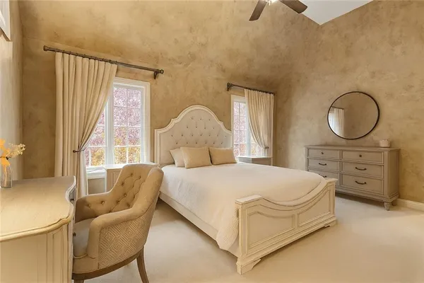 a bedroom with a bed a chair and a large window