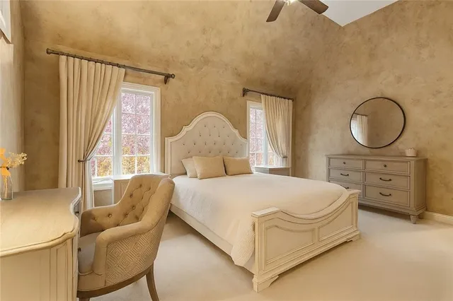 a bedroom with a bed a chair and a large window