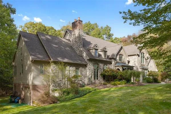 a view of a house next to a big yard and large trees