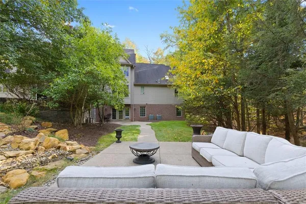 a view of a backyard with couches plants and large trees