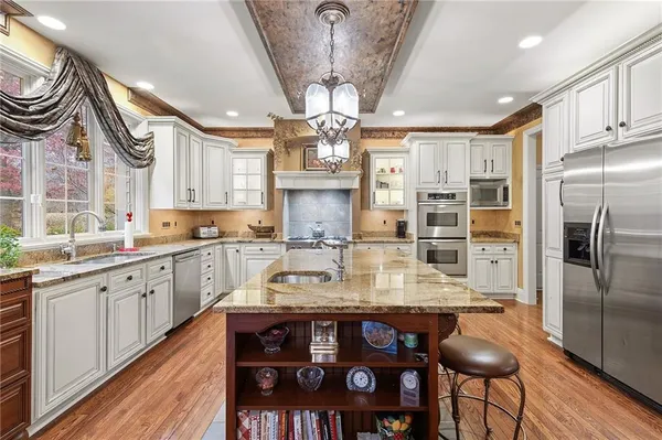 a kitchen with stainless steel appliances granite countertop a sink refrigerator dining table and chairs