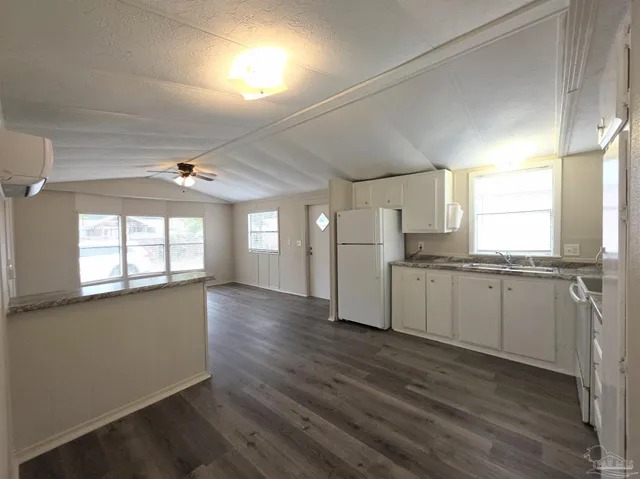 a kitchen with granite countertop a refrigerator and wooden floor