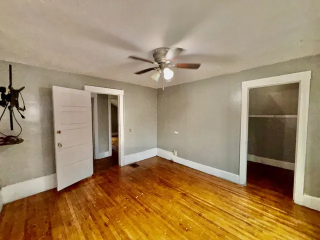 an empty room with closet and a ceiling fan