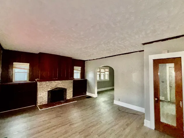 an empty room with fireplace and wooden floor