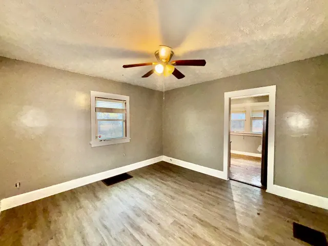 a view of an empty room with window and wooden floor