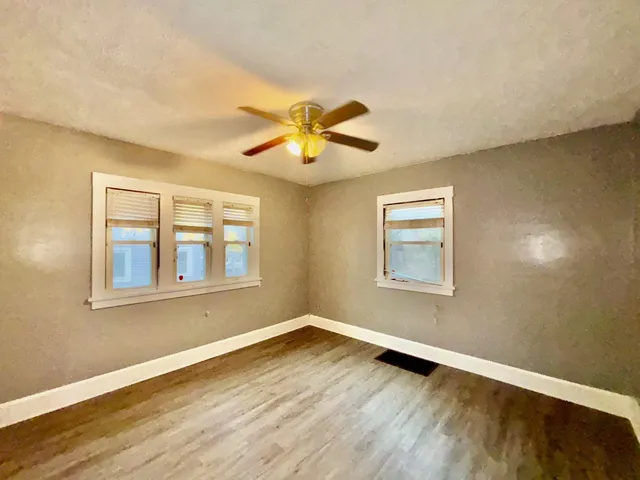 a view of an empty room with wooden floor and a window
