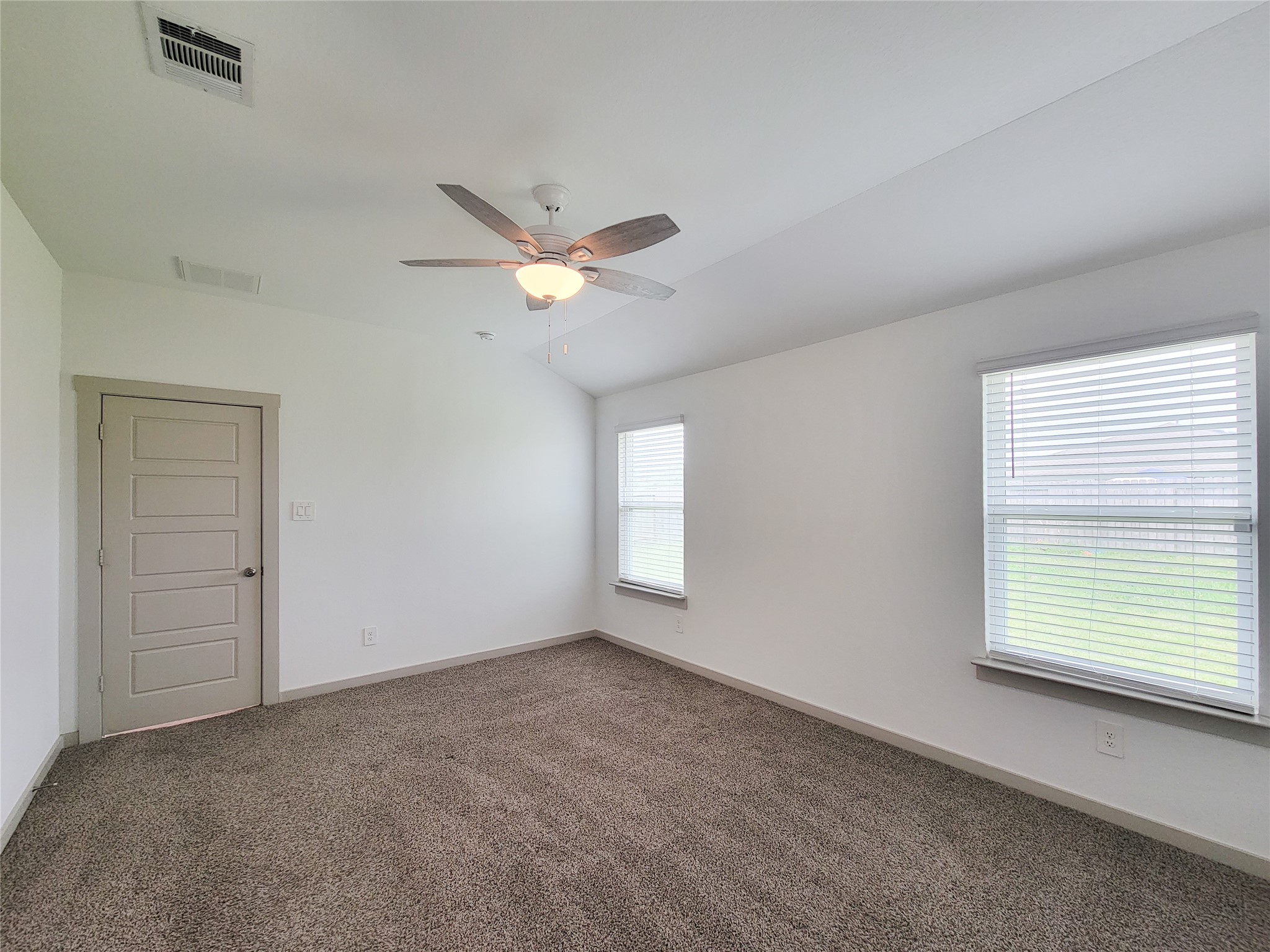 7722 Caldwell Crk Way Rosharon, TX 77583 - Photo 11 of 40 This photo showcases a bright, carpeted room with a ceiling fan, neutral walls, and two windows providing natural light. It has a closed door to one side, ideal for a bedroom or office space.