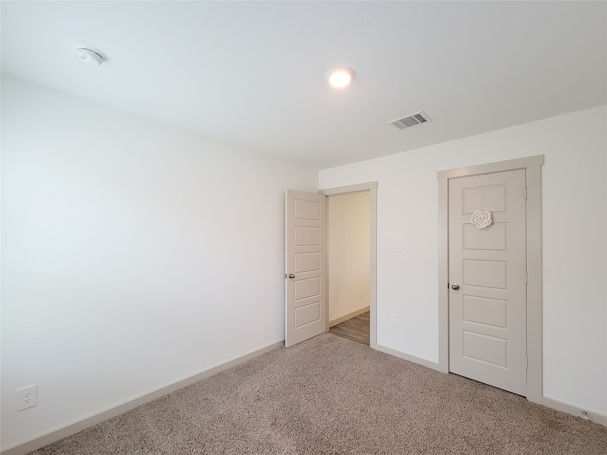 7722 Caldwell Crk Way Rosharon, TX 77583 - Photo 21 of 40 This room features neutral carpet, white walls, a ceiling light, and two doors with simple molding. It's a bright, versatile space ideal for a bedroom or office.