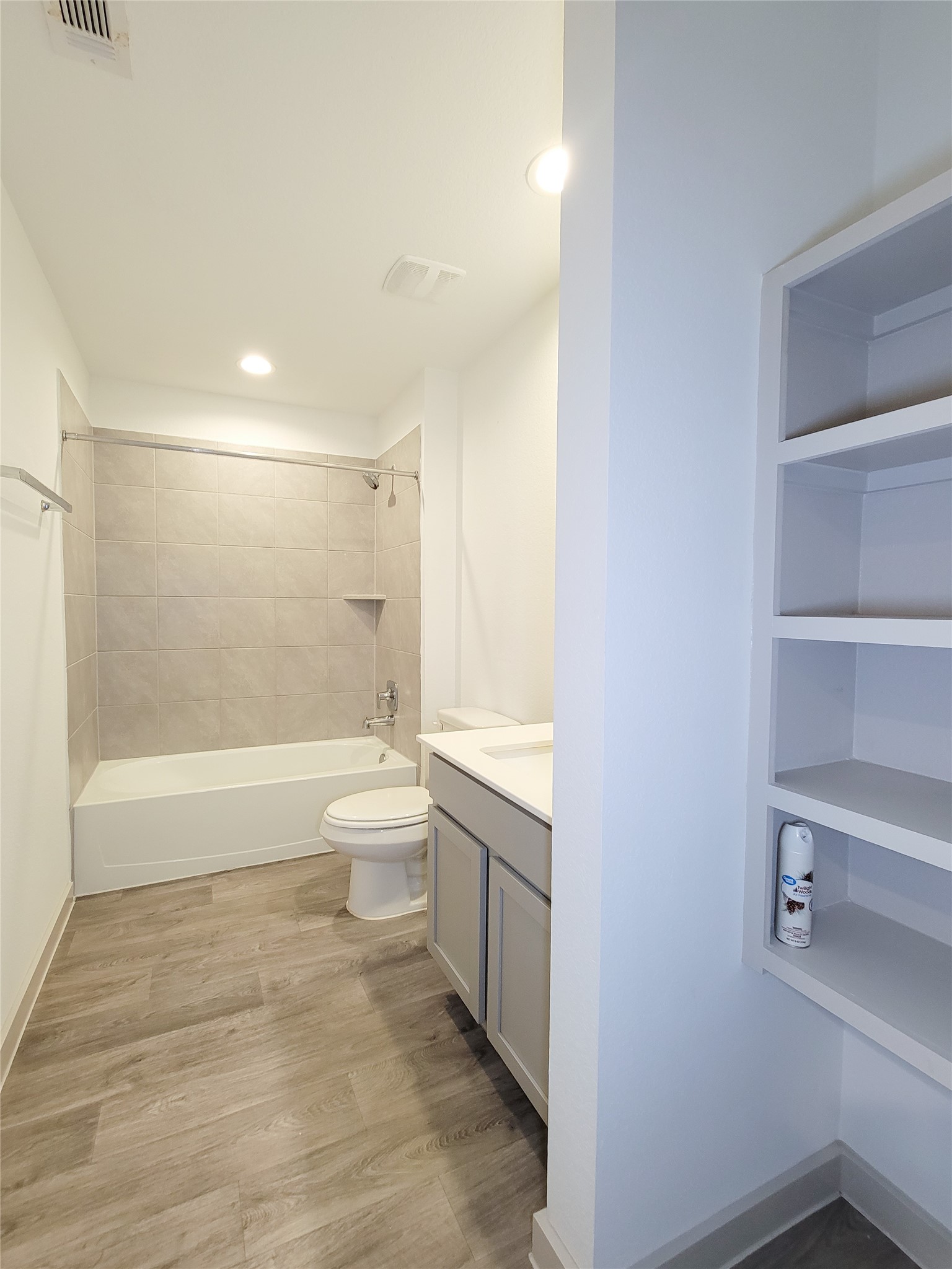 7722 Caldwell Crk Way Rosharon, TX 77583 - Photo 23 of 40 This bathroom features a modern design with light-colored tiles surrounding the bathtub, a sleek vanity with storage, open shelving, and wood-style flooring. Ideal for a minimalist aesthetic.