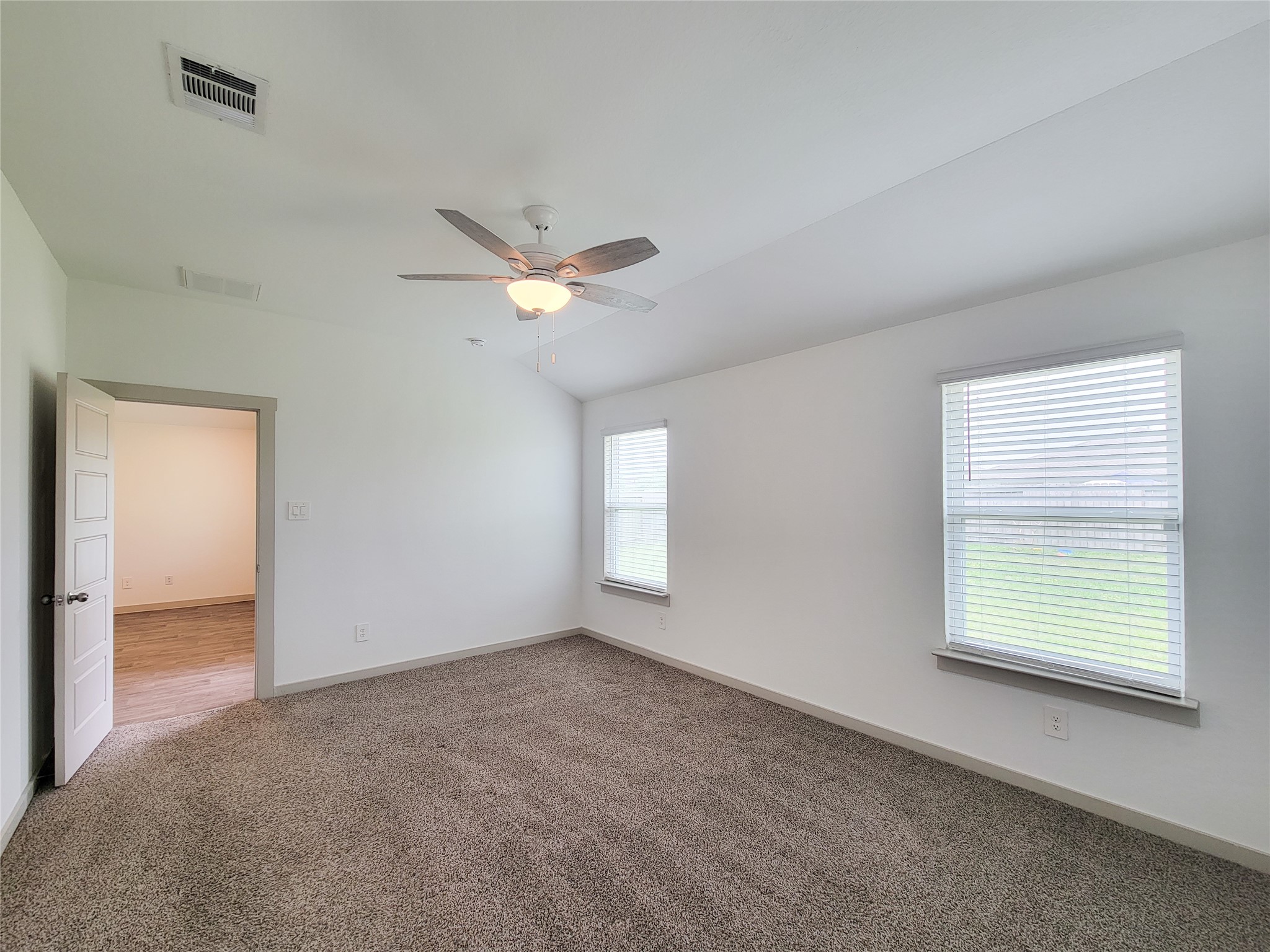 7722 Caldwell Crk Way Rosharon, TX 77583 - Photo 27 of 40 This room features plush carpeting, a ceiling fan, and ample natural light from two windows with blinds. The space is open and leads to another room with hardwood flooring.