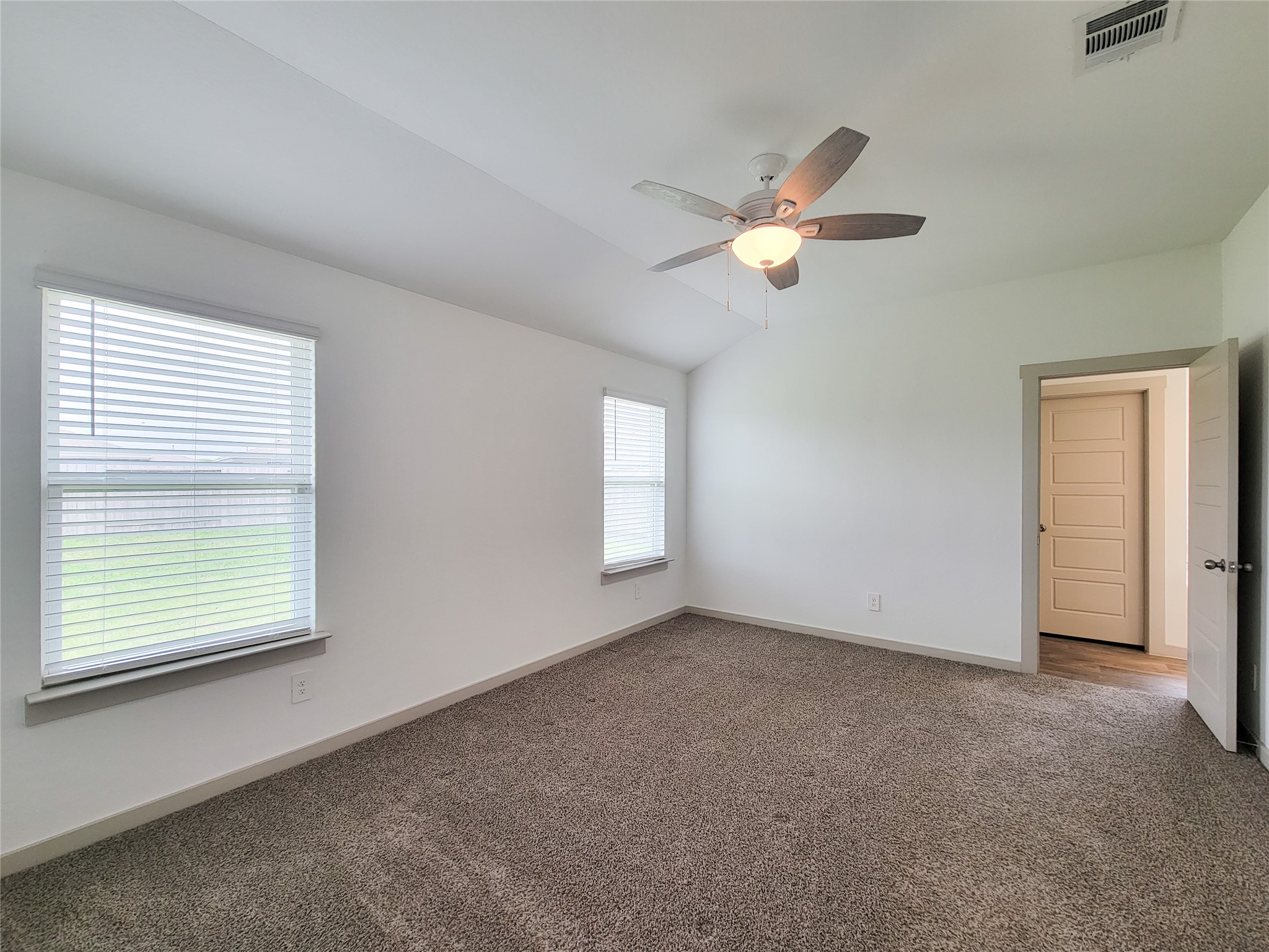7722 Caldwell Crk Way Rosharon, TX 77583 - Photo 28 of 40 This bright bedroom features plush carpeting, a ceiling fan, and ample natural light from two large windows. The neutral walls offer a clean and fresh look, while the door leads to an adjoining room or hallway.