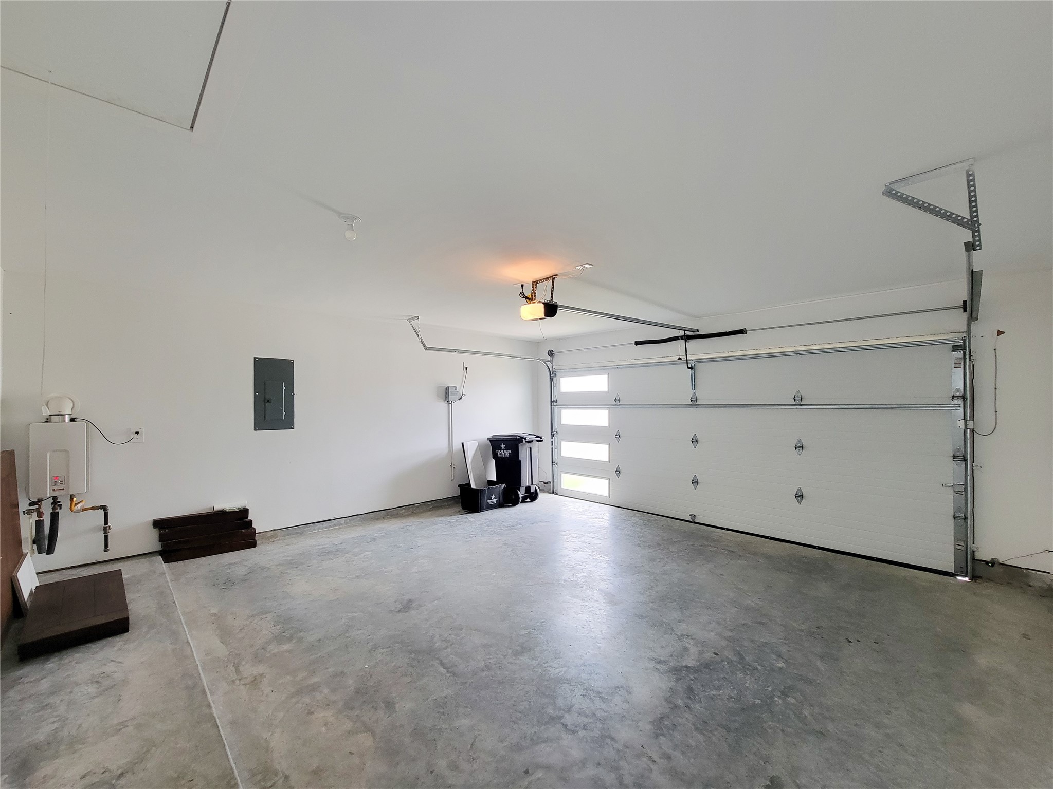 7722 Caldwell Crk Way Rosharon, TX 77583 - Photo 30 of 40 This is a clean, spacious garage with a concrete floor, white walls, and a large overhead door with windows. It's equipped with a water heater and electrical panel, providing practical storage and utility options.