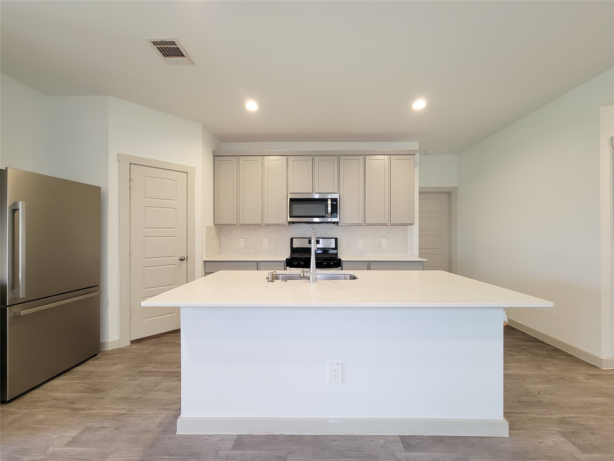 7722 Caldwell Crk Way Rosharon, TX 77583 - Photo 6 of 40 This modern kitchen features a spacious island with a sink, stainless steel appliances, and ample cabinet storage. It's bright and inviting, with sleek finishes and a clean design.