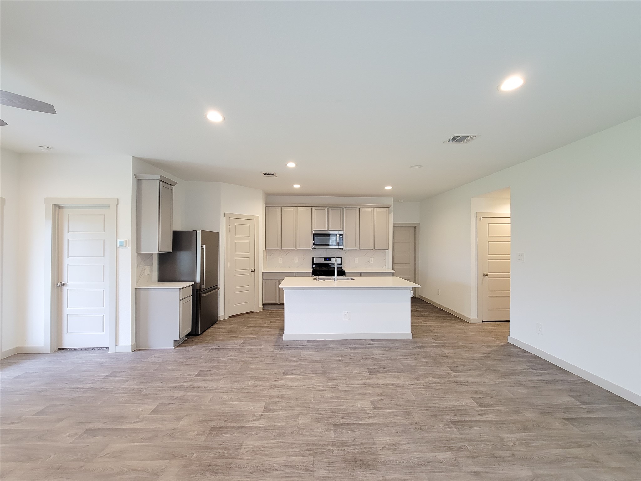 7722 Caldwell Crk Way Rosharon, TX 77583 - Photo 7 of 40 This photo showcases a modern, open-concept kitchen with light cabinetry, stainless steel appliances, and a central island. The space features sleek, wood-look flooring and recessed lighting, creating a bright and inviting atmosphere.