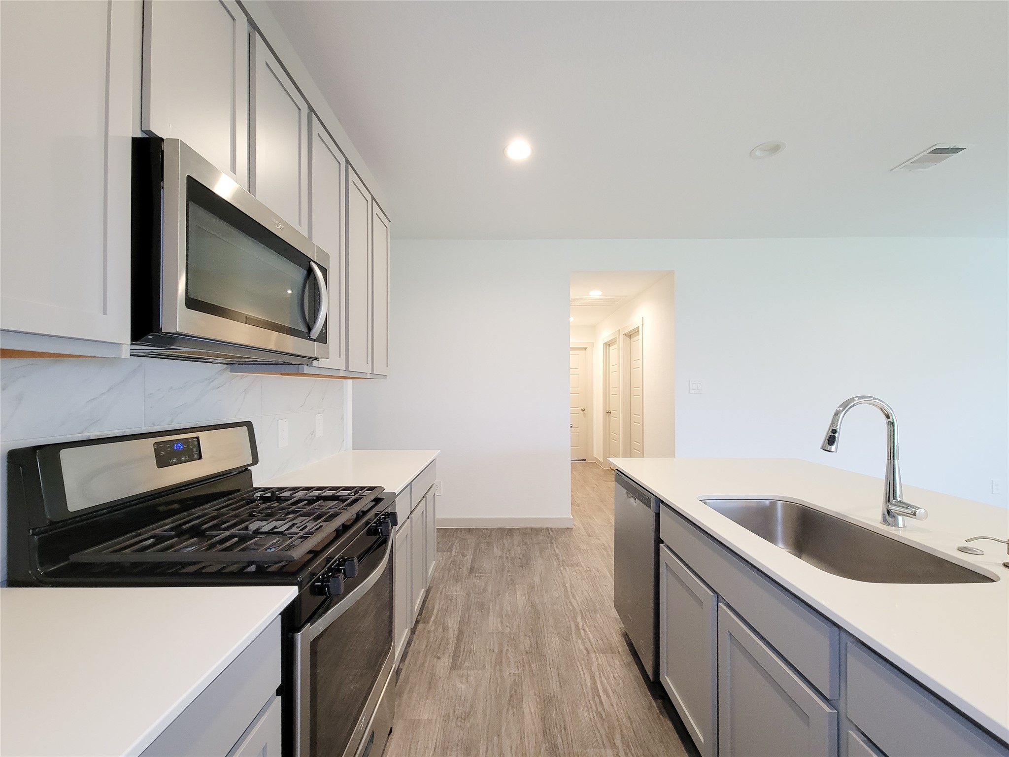 7722 Caldwell Crk Way Rosharon, TX 77583 - Photo 9 of 40 This modern kitchen features sleek stainless steel appliances, a gas stove, and a double sink. The cabinetry is elegant, offering ample storage, and the space is bright with recessed lighting and stylish flooring.