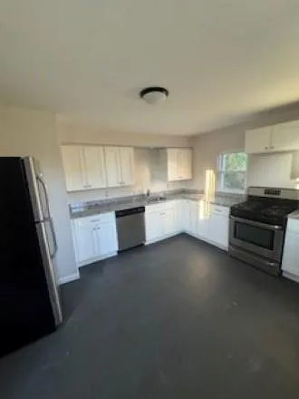 a kitchen with granite countertop a refrigerator and a stove top oven