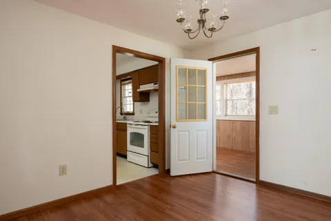 an empty room with wooden floor cabinet and windows