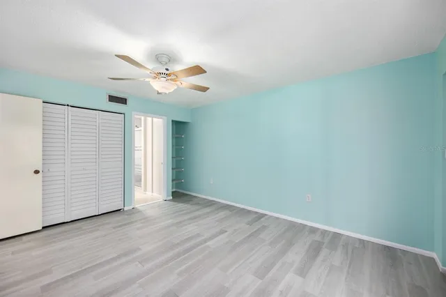 an empty room with wooden floor and ceiling fan