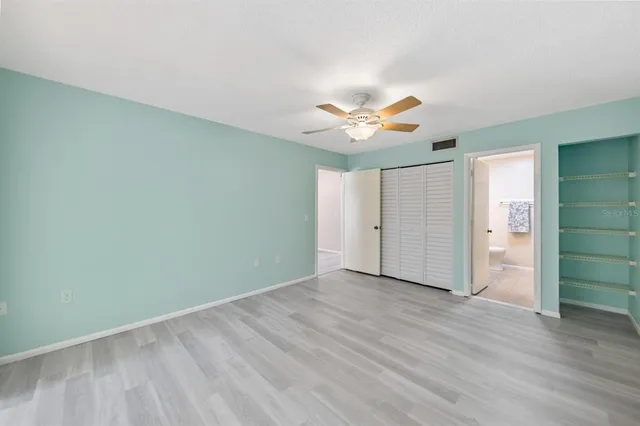 an empty room with wooden floor and a ceiling fan