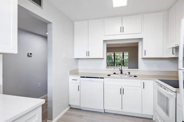 a kitchen with white cabinets sink and dishwasher