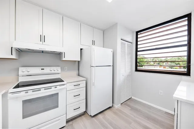 a kitchen with white cabinets and white appliances