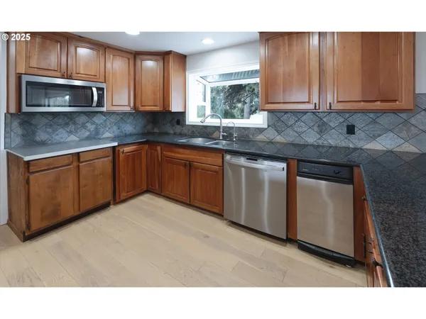 a kitchen with stainless steel appliances granite countertop a stove a sink dishwasher and a microwave