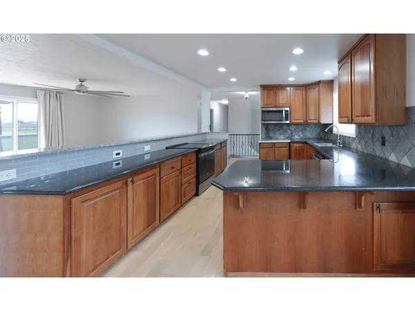 a kitchen with stainless steel appliances granite countertop a sink a stove and a wooden floors