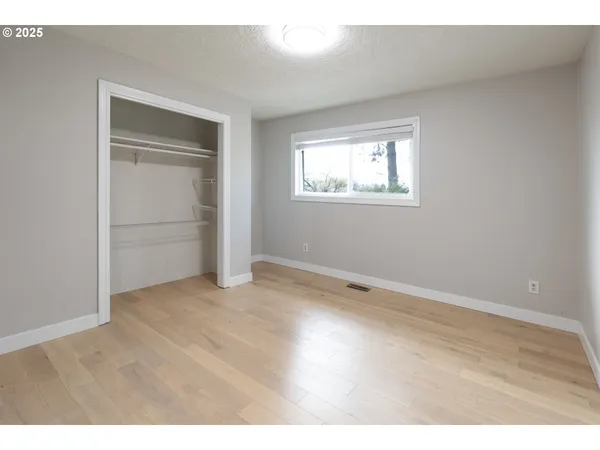 an empty room with wooden floor cabinet and windows