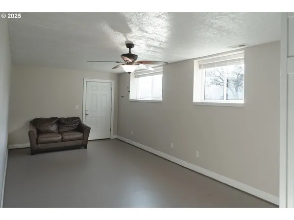 a view of a livingroom with wooden floor a ceiling fan and windows