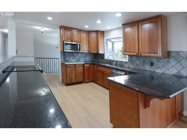 a kitchen with stainless steel appliances granite countertop a sink refrigerator and cabinets
