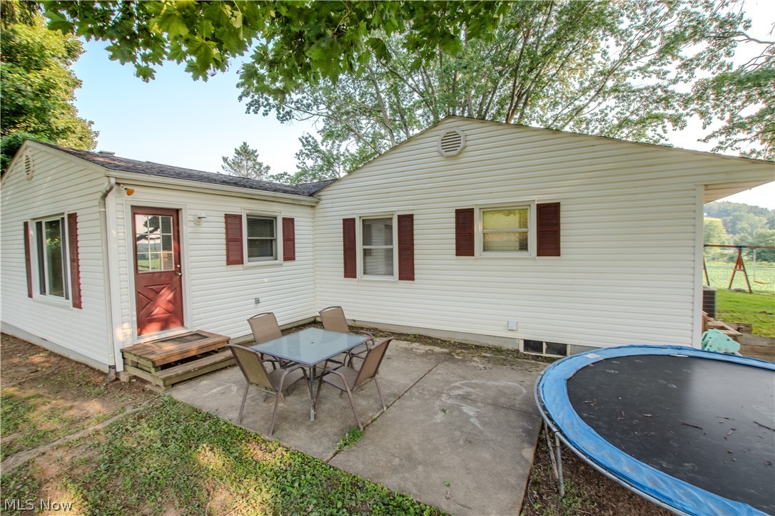 1757 Pleasant Valley Road Northeast New Philadelphia, OH 44663 - Photo 6 of 33 Exterior featuring white siding, dark red shutters, a red paneled door, a concrete patio, and a grass area