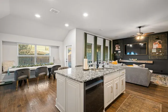 a view of living room with granite countertop kitchen island stainless steel appliances furniture stove and wooden floor