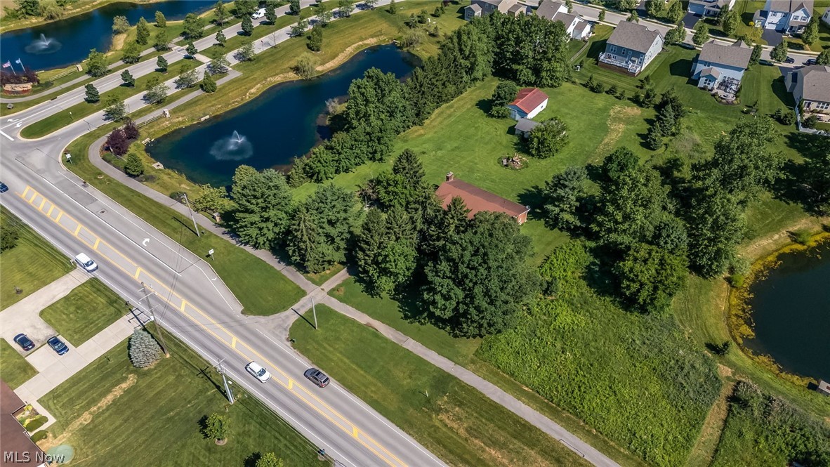 6890 Refugee Road Pickerington, OH 43147 - Photo 45 of 49 Expansive lot featuring mature trees, a red-roofed structure, and partial water frontage on a pond with a fountain