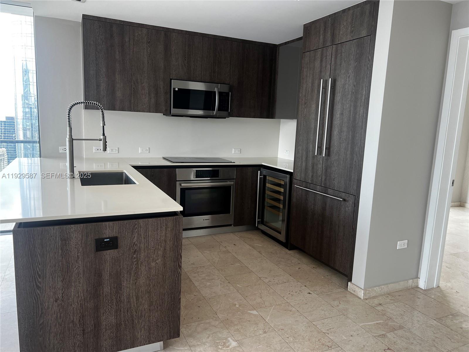 68 Southeast 6th Street, Unit 3401 Miami, FL 33131 - Photo 8 of 23 a kitchen with a sink and a refrigerator