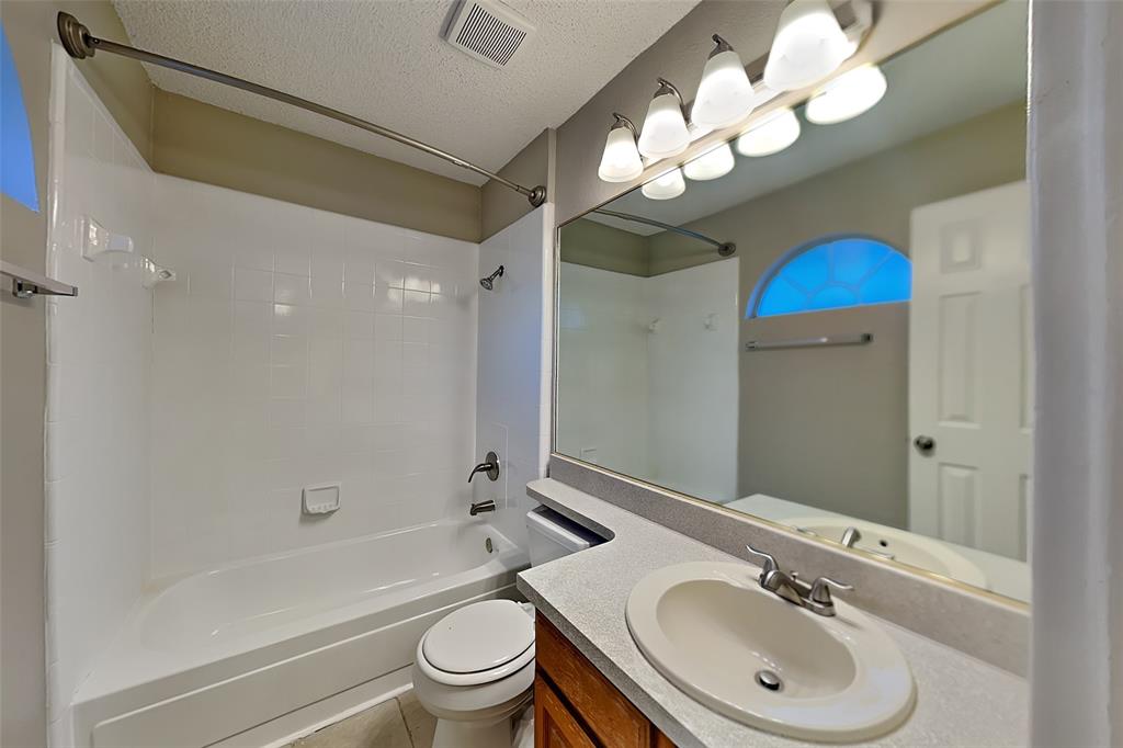 1213 Broken Arrow Trail Carrollton, TX 75007 - Photo 14 of 19 a bathroom with a sink a toilet a mirror a bathtub and shower