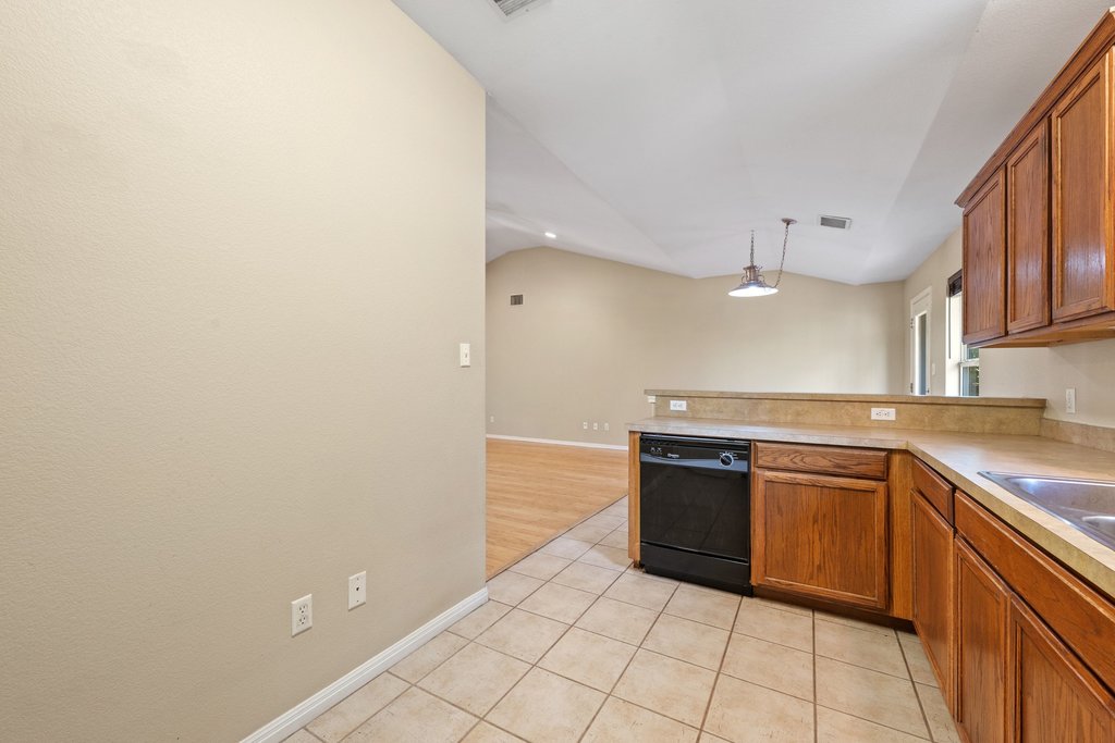 5208 Sioux Lane Austin, TX 78734 - Photo 8 of 35 A functional kitchen boasts warm wood cabinetry and durable tile flooring, openly connecting to the living area.