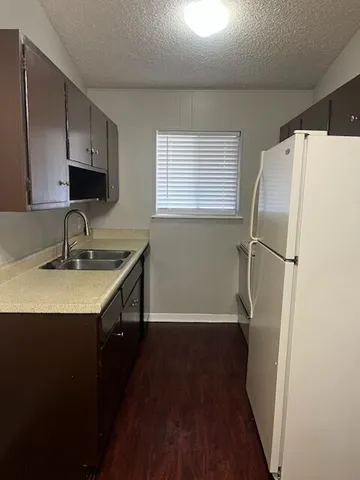 a kitchen with a sink a refrigerator a window and cabinets