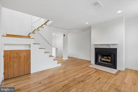 a view of an empty room with wooden floor fireplace and a window