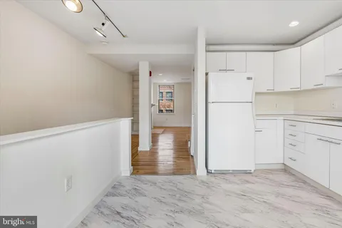 a view of a kitchen with refrigerator and white cabinets