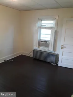 an empty room with wooden floor closet and windows