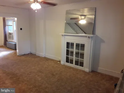 a view of an empty room with chandelier fan and fire place
