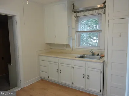 an empty room with wooden floor closet and windows