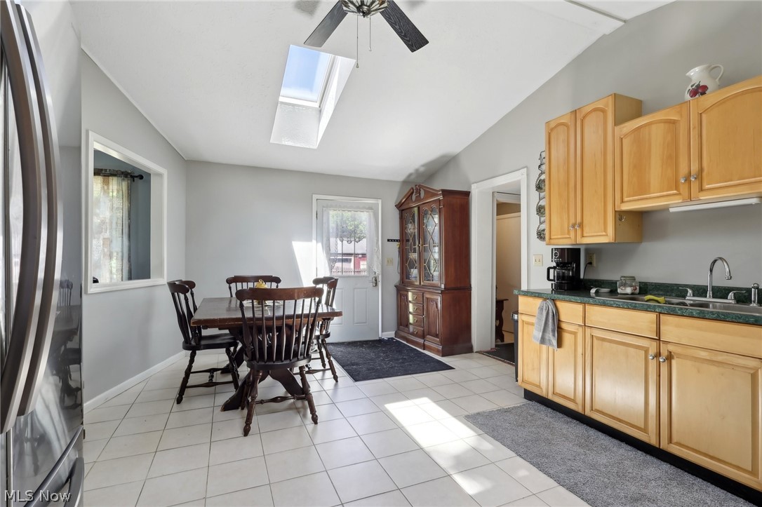16146 Ravenna Road Burton, OH 44021 - Photo 11 of 27 Kitchen featuring stainless steel fridge, light tile floors, vaulted ceiling with skylight, ceiling fan, and light brown cabinetry