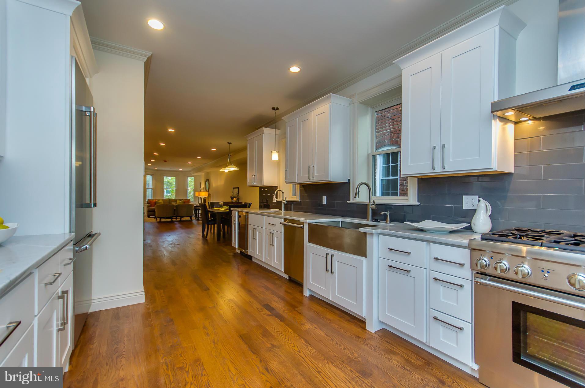 1128 Columbia Road Northwest Washington, DC 20009 - Photo 9 of 26 a large kitchen with stainless steel appliances granite countertop a stove a sink dishwasher and a oven with white cabinets