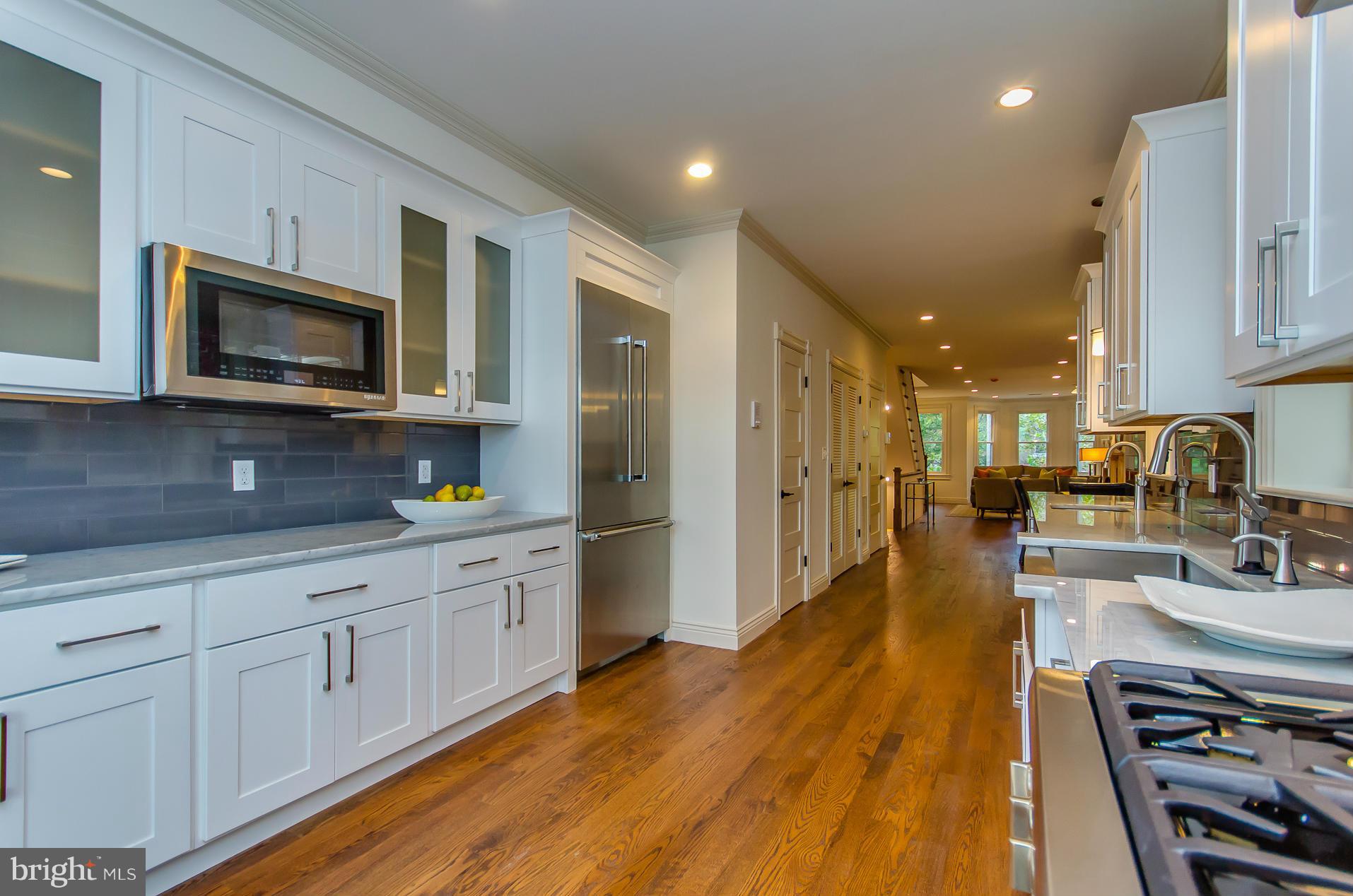 1128 Columbia Road Northwest Washington, DC 20009 - Photo 10 of 26 a kitchen with stainless steel appliances granite countertop a refrigerator a stove top oven a sink dishwasher and white cabinets with wooden floor