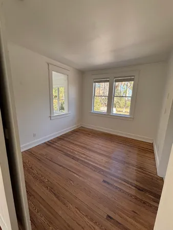a view of an empty room with wooden floor and window